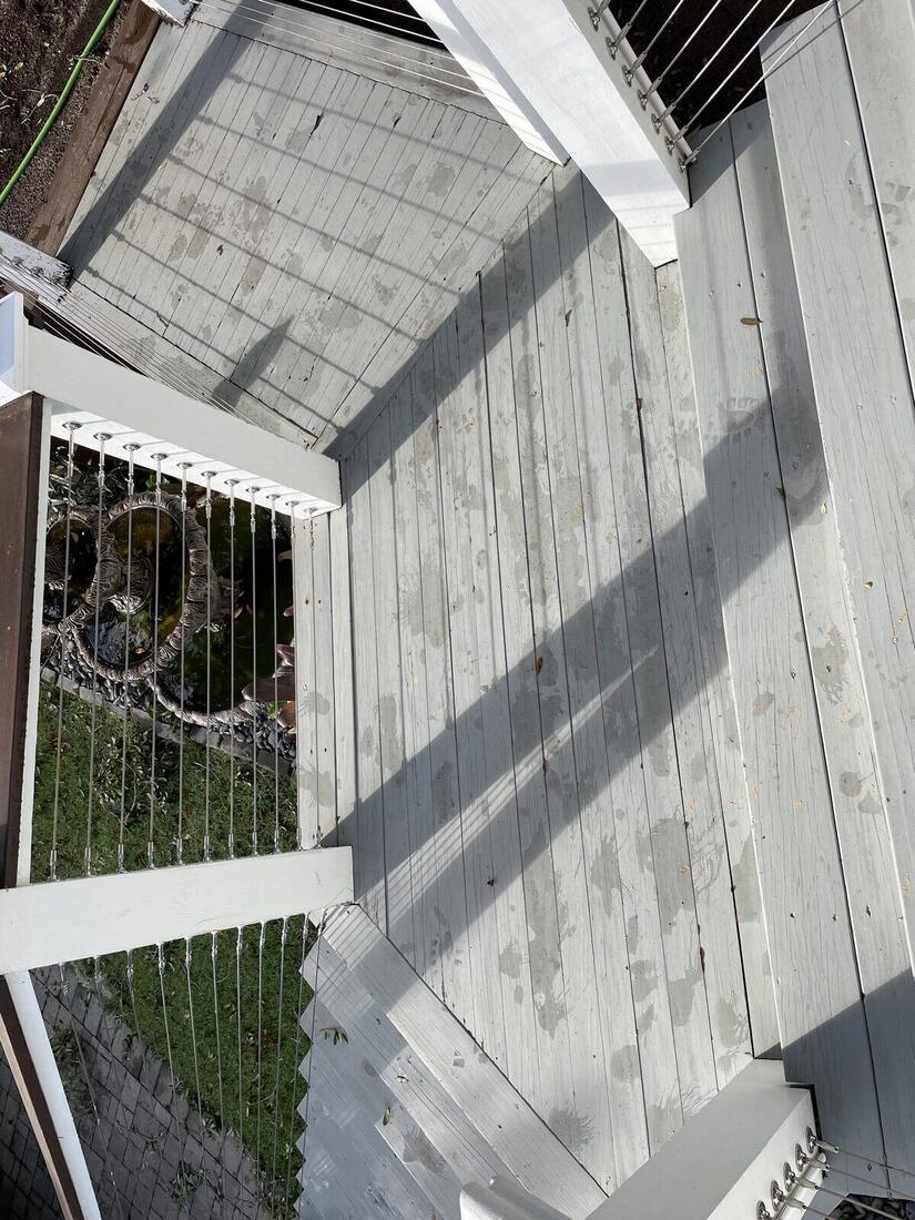 Overhead view of a finished elevated deck showing decking boards and cable railing from above.